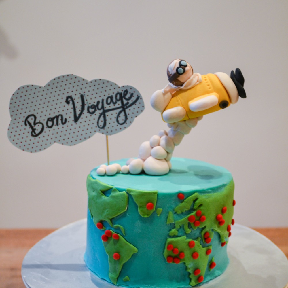 Gravity defying Bon woyage cake with an airplane cake topper and a little pilot. On the cake itself the visited places are marked on the map of the world, the cover is fully made out of fondant